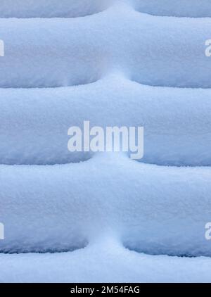Weiße schneebedeckte Oberfläche. Holzbohlen mit flauschigem, schmelzenden Schnee bedeckt. Stockfoto