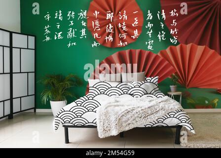 Die Inneneinrichtung des modernen, stilvollen Schlafzimmers mit schönem chinesischen Druck an der Wand Stockfoto