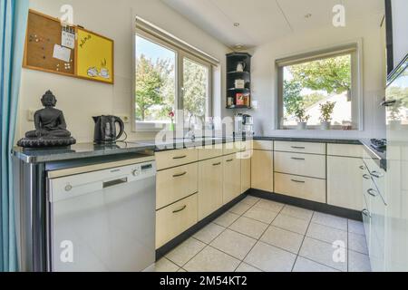 Ein Küchenbereich mit weißen Schränken und schwarzen Ablageflächen auf den Ablagen auf diesem Foto wird von innen aufgenommen Stockfoto