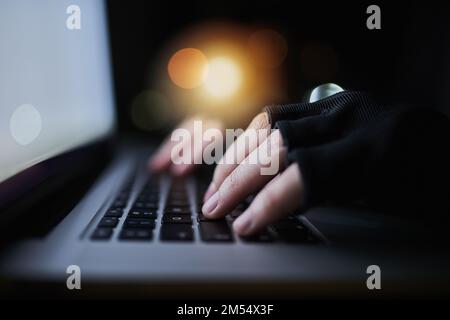 Wenn es online ist, zur Hölle, es zu finden. Ein nicht erkennbarer Computer-Hacker, der spät in der Nacht einen Laptop benutzt. Stockfoto