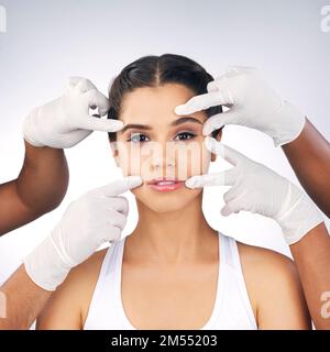 Addicted to beauty. Studio portrait of a beautiful young woman posing with gloved hands touching her face against a grey background. Stockfoto