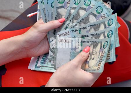 Ein Blick von oben auf weibliche Hände in rotem Kleid, die viele armenische 20000 Drachenscheine halten und zählen Stockfoto