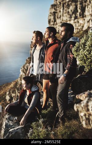 Manchmal kann man nicht anders, als zu starren. Eine Gruppe von Freunden, die die Aussicht während der Wanderung in den Bergen bewundern. Stockfoto