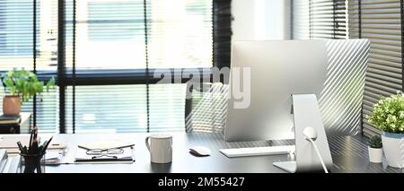 Moderne Büroeinrichtung mit Computer, Tasse Kaffee, Dokument, Lieferung und Topfpflanzen auf einem leeren Holztisch Stockfoto