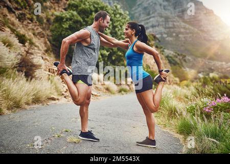 Wir helfen uns gegenseitig. Ein junges, attraktives Paar, das für einen Marathon im Freien trainiert. Stockfoto