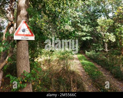 Warnschild am Eingang eines deutschen Waldes mit der Aufschrift Zecken - Zecken. Stockfoto