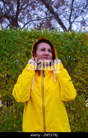 Das Porträt eines Mädchens in einer gelben Jacke vor dem Hintergrund von Bäumen Stockfoto