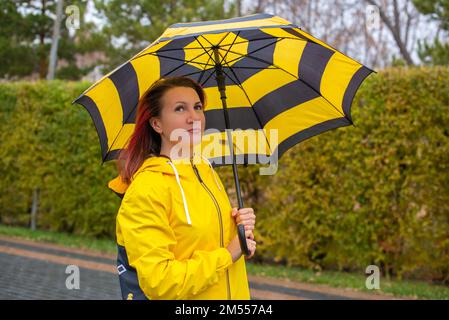 Mädchen in Gelb mit gestreiftem Regenschirm Stockfoto