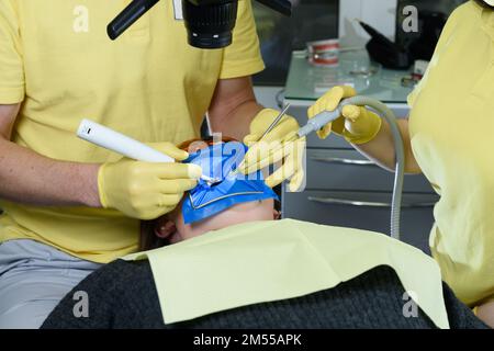 Nahaufnahme von operativ tätigen aufmerksamen Ärzten bei der Installation von Zahnimplantaten in den Mund des Patienten in einer modernen Zahnklinik. Stockfoto