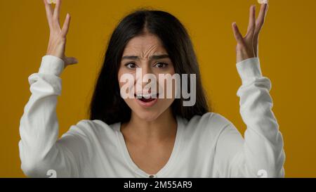 Weibliches Porträt in gelbem Studiohintergrund indische ethnische Frau emotionale Frau Frau, die überwältigende Kopf-Geste zeigt, schockierte überwältigende Explosion Stockfoto