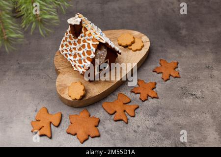 Lebkuchenhaus mit Keksen. Nahaufnahme eines süßen heimischen Desserts mit Glasur auf Grau Stockfoto