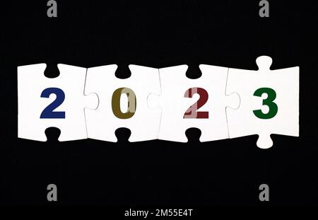 Vier Puzzleteile mit den Zahlen 20223 sind auf schwarzem Hintergrund miteinander verbunden Stockfoto