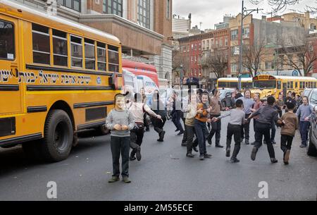 Orthodoxe jüdische Jeschiva-Studenten machen ihre Pause in einer abgeschlossenen Straße in Brooklyn, New York. Stockfoto