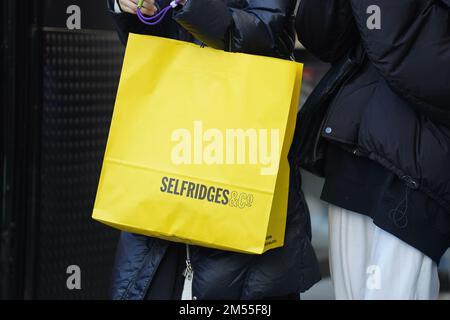 Käufer, die Selfridges Kaufhaustaschen auf der Oxford Street in London während der Verkäufe am Boxing Day mit sich führen. Die Käufer am zweiten Weihnachtsfeiertag werden sich dieses Jahr besonders bemühen, das beste Preis-Leistungs-Verhältnis zu erhalten, da die täglichen Rechnungen in die Höhe schnellen. Foto: Montag, 26. Dezember 2022. Stockfoto