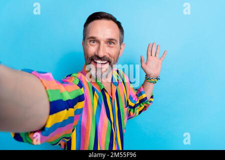 Selfie Nahaufnahme eines erwachsenen Mannes Tragen Sie ein altmodisches Retro-Outfit graues Haar highfive Palm Hello Abonnenten isoliert auf blauem Hintergrund Stockfoto