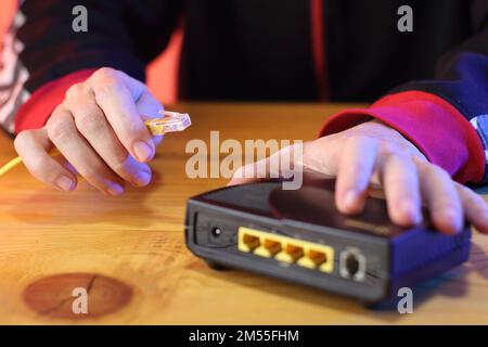 Internetkabel mit altem adsl-Modem auf dem Tisch von einer Person im Hintergrund verbunden Stockfoto