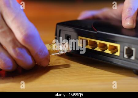 Internetkabel mit altem adsl-Modem auf dem Tisch von einer Person im Hintergrund verbunden Stockfoto
