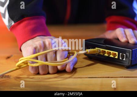 Gewaltsames Abreißen des Internetkabels vom adsl-Modem durch eine Person im Hintergrund Stockfoto