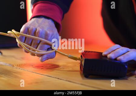 Gewaltsames Abreißen des Internetkabels vom adsl-Modem durch eine Person im Hintergrund Stockfoto