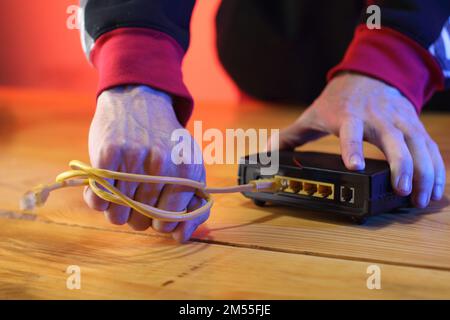 Gewaltsames Abreißen des Internetkabels vom adsl-Modem durch eine Person im Hintergrund Stockfoto
