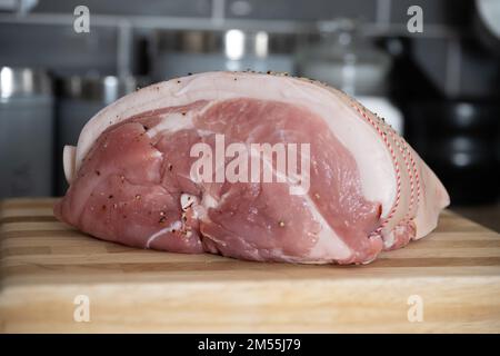 Frisch geschnitten und gewürzt mit Meersalz und gebrochenem schwarzem Pfeffer Schweinebeinchen auf einem Holzbrett Stockfoto