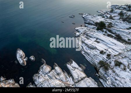Seascape mit schneebedeckten Felsen. Luftaufnahme der Meereslandschaft mit schneebedeckten Felsen. Stockfoto