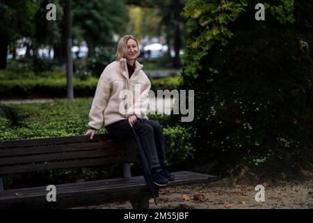 Eine Frau sitzt auf einer Bank in einem Herbstpark. Stockfoto