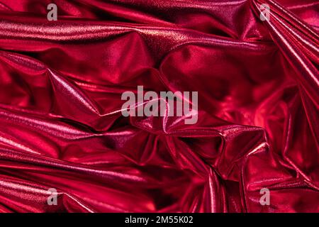 Elegantes, glattes Satingewebe lässt sich falten. Farbe des Jahres 2023 Viva Magenta. Luxuriöse Rückwand aus gedrehtem Stoff Stockfoto