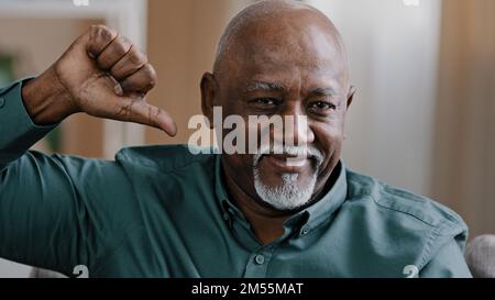 Das Porträt eines selbstbewussten älteren afroamerikanischen Mannes im Haus, der vor die Kamera schaut, zeigt negative Emotionen, die ein alter Geschäftsmann zeigt, der nicht mag Stockfoto