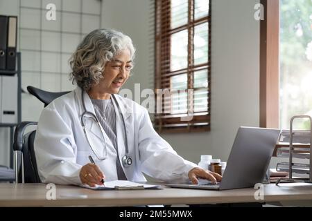Ärztin im Laborkittel arbeitet und notiert sich Informationen über den Patienten Stockfoto