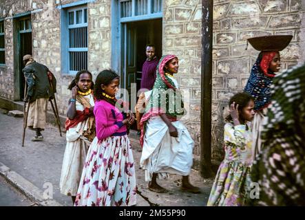 Äthiopien, 1970er, Harar, junge Frauen und Mädchen, die auf den Markt eilen, behinderter Mann, der auf Krücken läuft, Region Harari, Ostafrika, Stockfoto