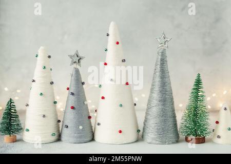 Handgefertigte Weihnachtsbäume. Garnumwickelte Kegelbäume. WEIHNACHTSGESCHENKE. DIY-Konzept Stockfoto