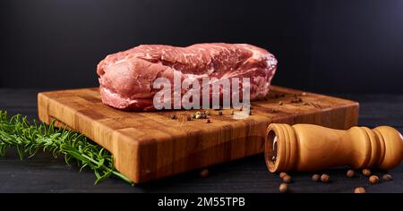 Rohes Fleisch. Rohes Rindfleischsteak auf ein Schneidebrett mit Rosmarin und Gewürzen. Stockfoto