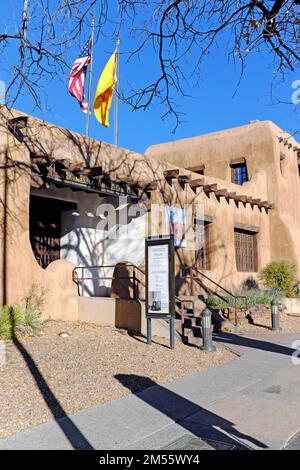 Das 1917 gegründete New Mexico Museum of Art auf der West Palace Avenue in Santa Fe, New Mexico, mit der Flagge der USA und New Mexicos am 11. November 2022. Stockfoto