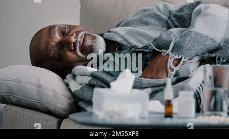Alter, kahler, bärtiger, übergewichtiger Mann mittleren Alters, afrikanischer Großvater, kranker Geschäftsmann, der zu Hause auf dem Sofa liegt, mit hohem Fieber, Erkältung Stockfoto