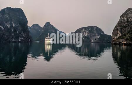 Touristenboot am Morgen zwischen den Kalksteininseln in der Halong-Bucht, Vietnam Stockfoto