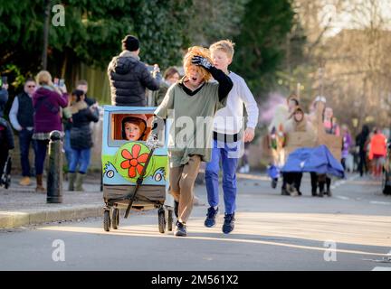 East Hoathly, Großbritannien. 26. Dezember 2022. Pram-Rennen am zweiten Weihnachtsfeiertag: Teams in einem schicken Kostümrennen durch das Dorf East Hoathly in East Sussex sammeln Spenden für lokale Wohltätigkeitsorganisationen. Die jährliche Veranstaltung beginnt und endet im Kings Head Pub im Zentrum des Dorfes. Kredit: Jim Holden/Alamy Live News Stockfoto