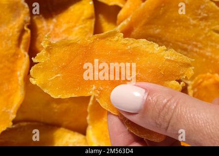 Getrocknete Mangomaterieschichten auf einem Weißen. Draufsicht. Nahaufnahme. Mango-Chips-Hintergrund. Getrocknete, knusprige Fruchtscheiben, Stücke. Haufen sonnengetrockneten Gelbes fr Stockfoto
