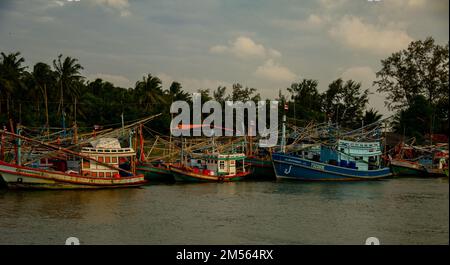 Dezember 16 2022 - Pathio Thailand Chumphon Gegend - farbenfrohe Fischerboote, die mit Flut vom Meer kommen und aufgrund des Sturms an Land gespült wurden. Stockfoto