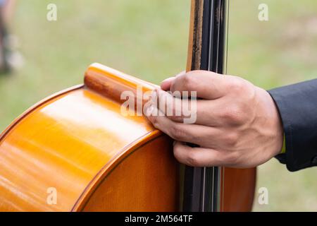 Die Hand eines Cellisten hält das Cello am Hals, der Künstler bereitet sich auf die musikalische Vorstellung vor Stockfoto