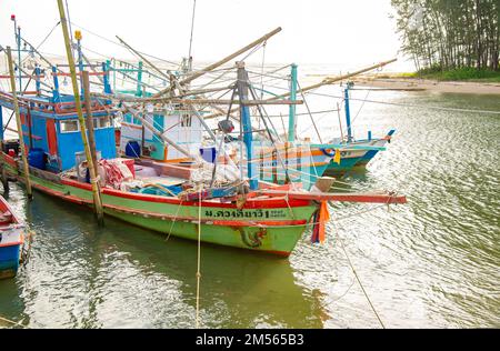 Dezember 16 2022 - Pathio Thailand Chumphon Gegend - farbenfrohe Fischerboote, die mit Flut vom Meer kommen und aufgrund des Sturms an Land gespült wurden. Stockfoto