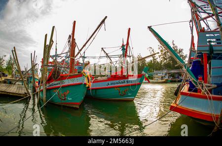 Dezember 16 2022 - Pathio Thailand Chumphon Gegend - farbenfrohe Fischerboote, die mit Flut vom Meer kommen und aufgrund des Sturms an Land gespült wurden. Stockfoto