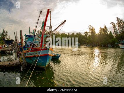 Dezember 16 2022 - Pathio Thailand Chumphon Gegend - farbenfrohe Fischerboote, die mit Flut vom Meer kommen und aufgrund des Sturms an Land gespült wurden. Stockfoto