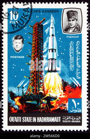 SÜDJEMEN - CIRCA 1967: Ein im südjemen aufgedruckter Stempel des Staates Quaiti in Hadhramaut zeigt Saturn V und Apollo, die am Startplatz in Cape Kennedy beginnen; Stockfoto