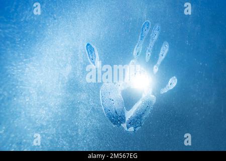 Warme Handspuren auf gefrorenem Glas und helles Sonnenlicht draußen Stockfoto