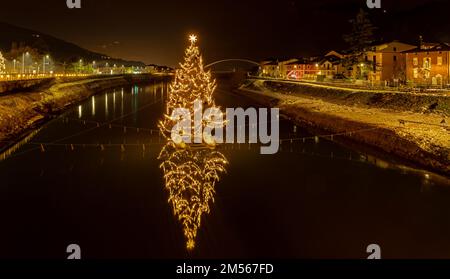 Der große Weihnachtsbaum an der Etsch - San Michele all'Adige in der Provinz Trient. Nachtfotografie. Stockfoto