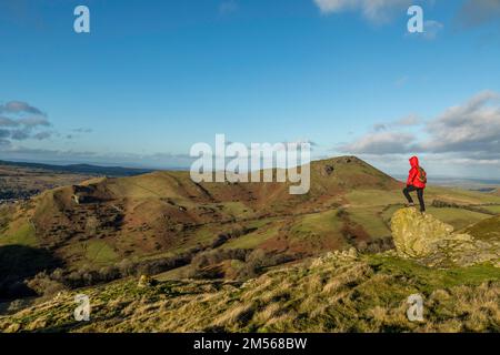 Eine weibliche Wanderin blickt auf Caer Caradoc, einen Hügel in Shropshire, England, mit einer Bronzezeit oder Iron Age Hill Fort. Stockfoto