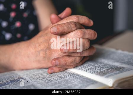 Eine alte Frau liest die Bibel, die Hände sind dicht. Stockfoto