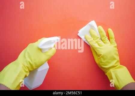 Hand in gelbe Gummihandschuhe mit Reinigungstisch für Sprühflaschen Stockfoto