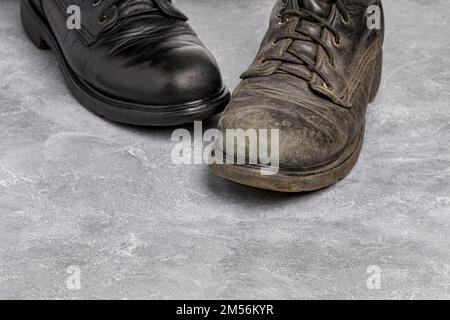 Vor und nach polierten und schmutzigen Arbeitsstiefeln aus Leder. Schuhcreme, Schuhpflege und -Reinigung. Stockfoto